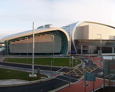 Modern architectural design of a large building with a curved facade, surrounded by roads and green space.