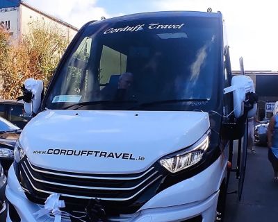 Newly branded Corduff Travel coach with decorative ribbons, parked at a travel service location, showcasing modern design and spacious front.